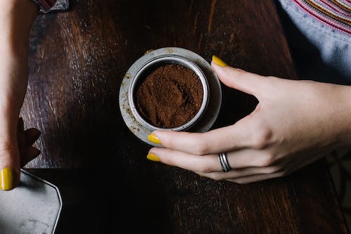 woman holding a bowl of ground coffee for pothos